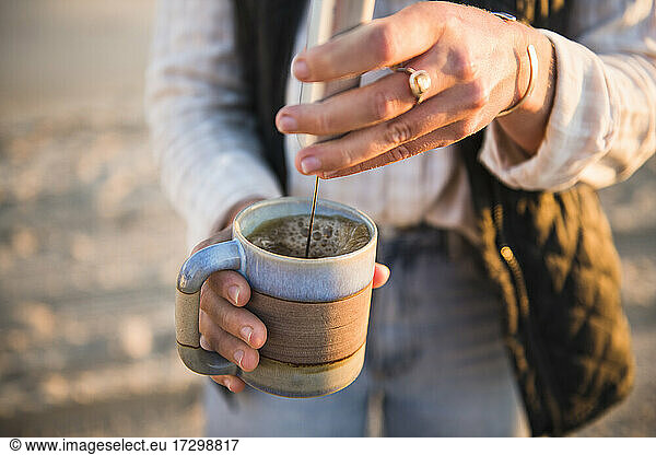 Young woman emulsifying coffee while beach car camping
