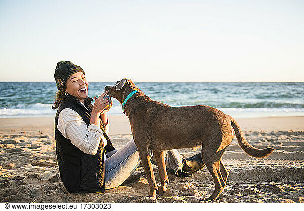 Young woman enjoying drink in mug while beach car camping with dog