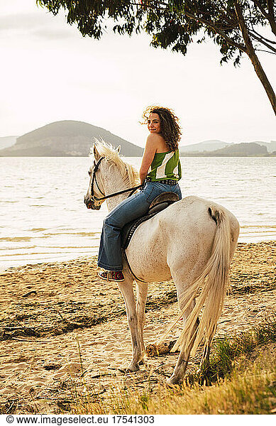 Young woman enjoying horse riding at waterfront