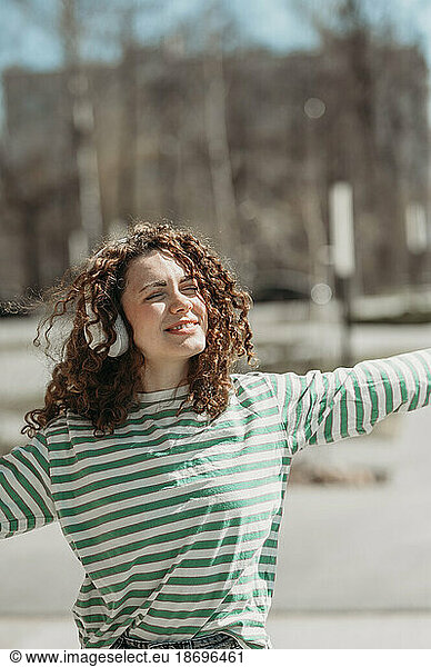 Young woman enjoying listening to music through headphones at sunny day