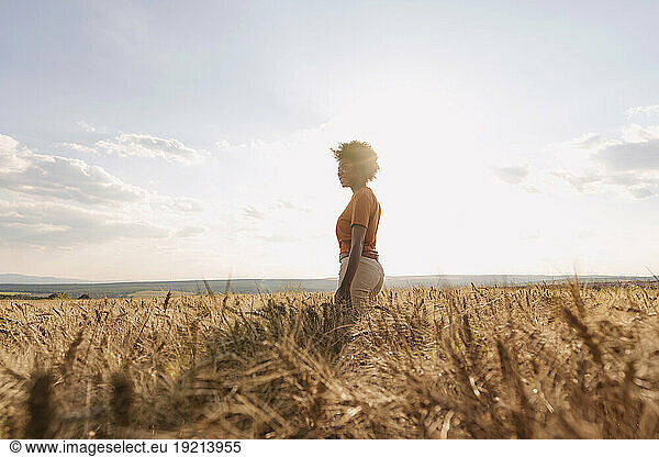 Young woman enjoying solitude in barley field at sunset