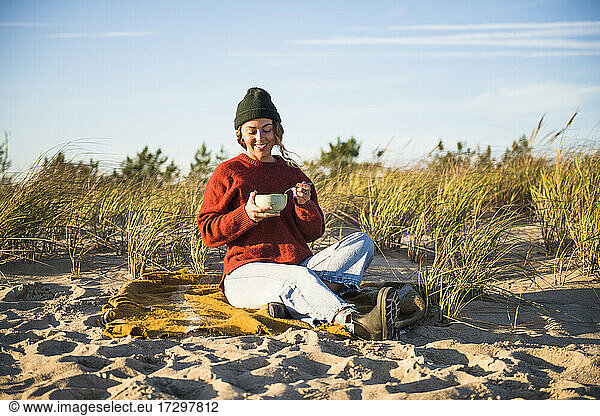 Young woman enjoying soup while beach car camping alone