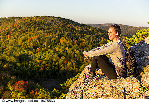 Young woman enjoying view from trail on Beehive in fall in Acadia National Park  Maine  USA