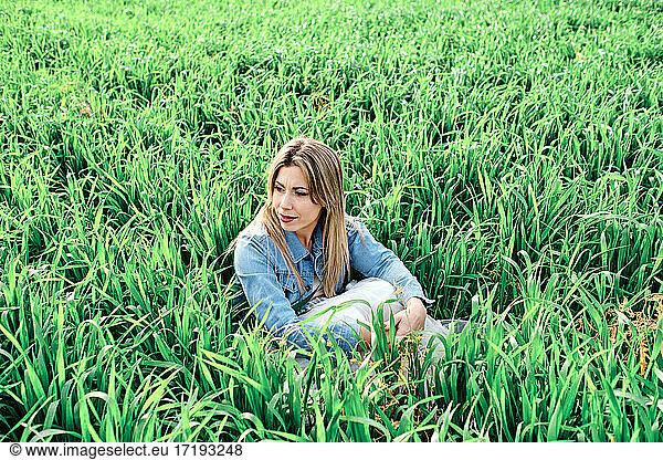 young woman enjoys sitting on the grass on the field