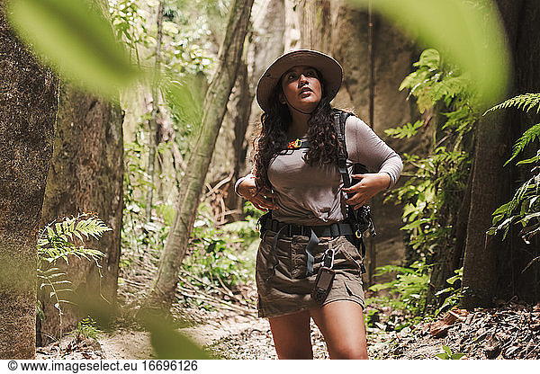 Young woman exploring a canyon surrounded by tropical vegetation.