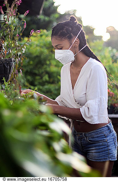 Young woman gardening in face mask