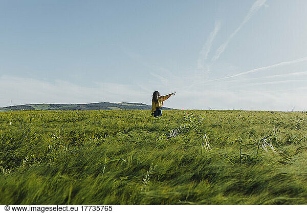 Young woman gesturing standing in meadow on sunny day