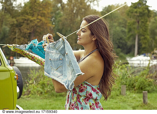 Young woman hanging out washing clothes on clothesline by camper van