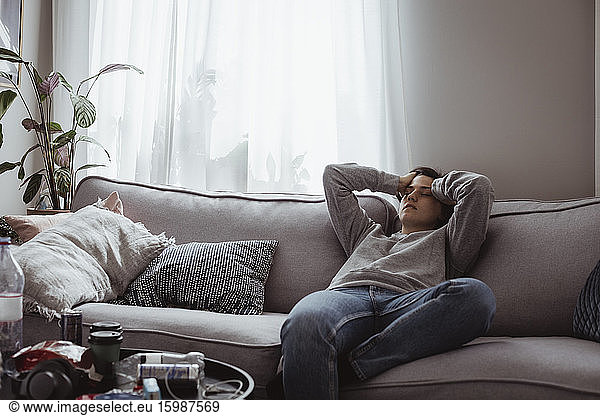 Young woman having headache sitting on sofa at home