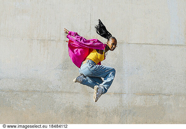 Young woman hip hop dancing in front of wall