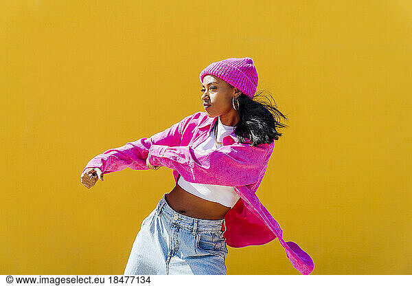 Young woman hip hop dancing in front of yellow wall
