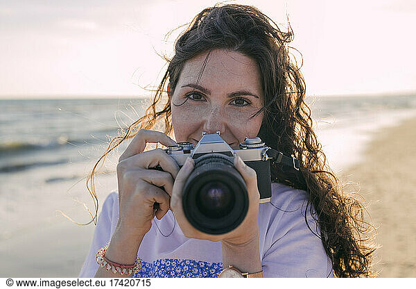 Young woman holding camera at beach