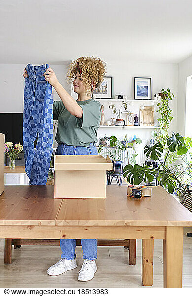Young woman holding checked jeans at home