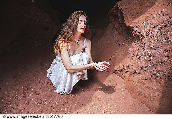 Young woman holding red sand in cupped hands