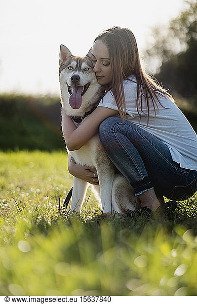 Young woman hugging her dog on a meadow