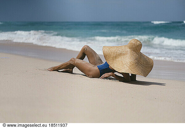 Young woman in a big straw hat on the ocean.