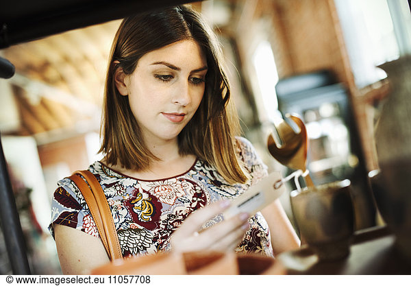 Young woman in a shop  looking at a price tag.