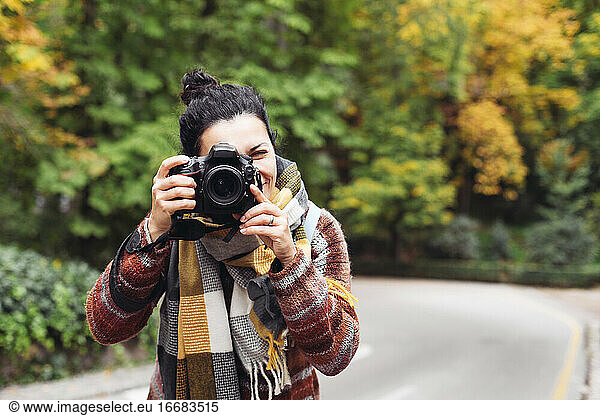 Young woman in a sweater with a camera taking pictures  autumn forest