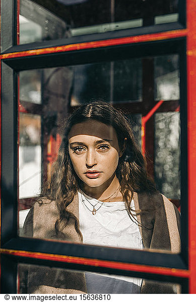 Young woman in a telephone box  looking at camera