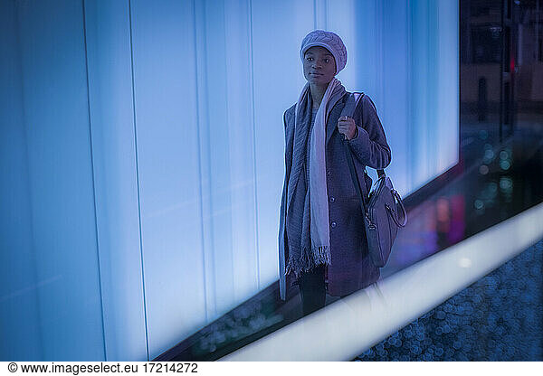 Young woman in scarf and hat in modern corridor