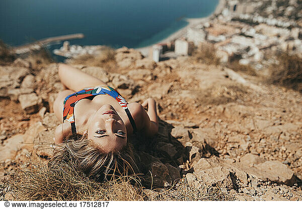 Young woman in swimsuit lying on a cliff above the coastal city of Almeria  Spain