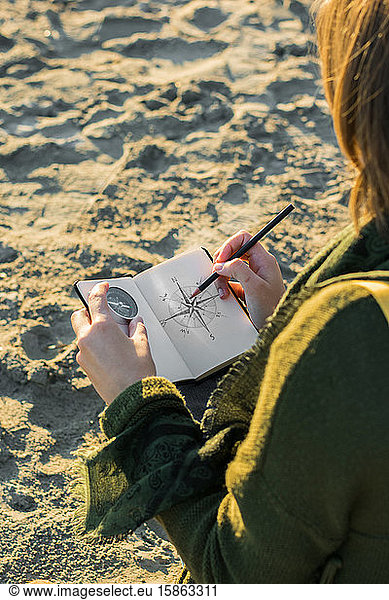 Young woman is drawing a compass in a notebook. Lifestyle  travel