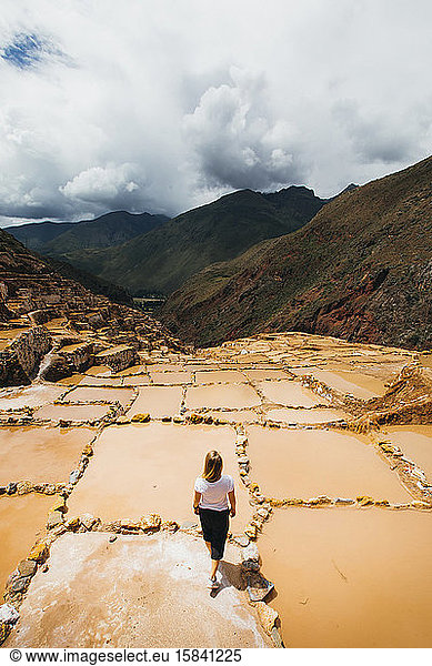 Young woman is standing near the famous salt mines in Peru