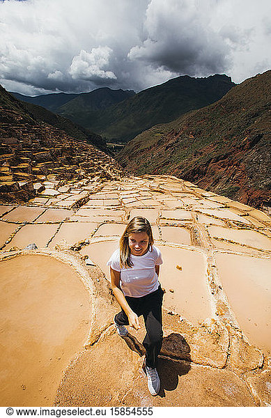 Young woman is walking near the famous salt mines in Peru
