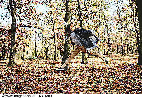 Young woman jumping in autumn forest