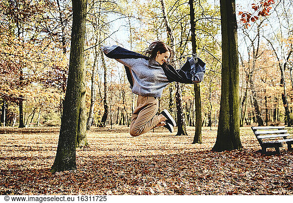 Young woman jumping in autumn forest