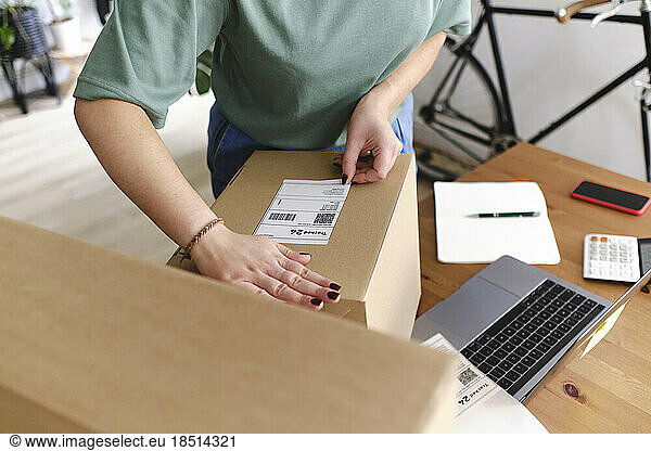 Young woman labeling cardboard boxes at desk
