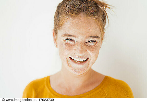 Young woman laughing in front of white background