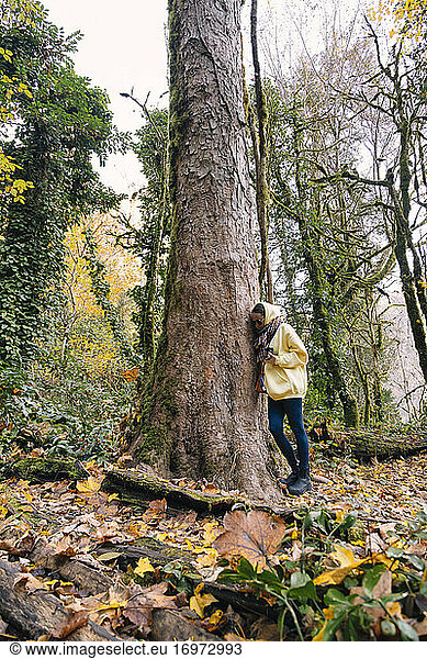 Young woman leaning against tree trunk