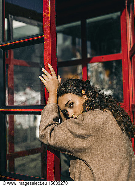 Young woman leaning on a telephone box