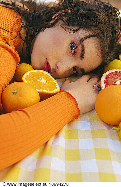Young woman leaning on table with citrus fruits