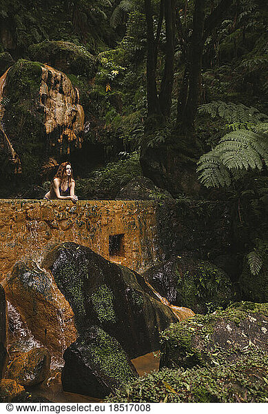 Young woman leaning on wall in forest