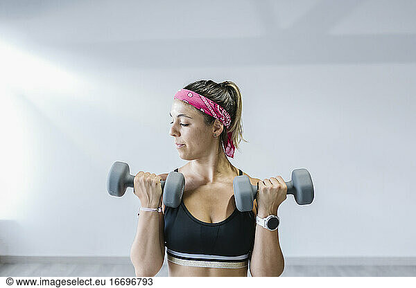 Young woman lifting dumbbells in gym