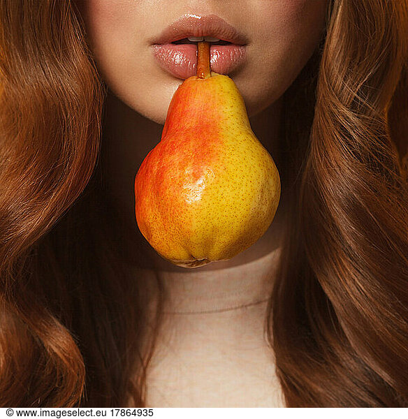 young woman lips holding fresh ripe pear