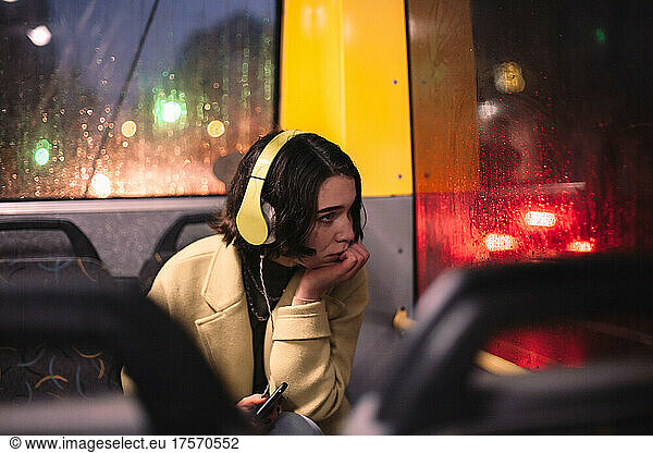 Young woman listening music in headphones traveling in trolley bus
