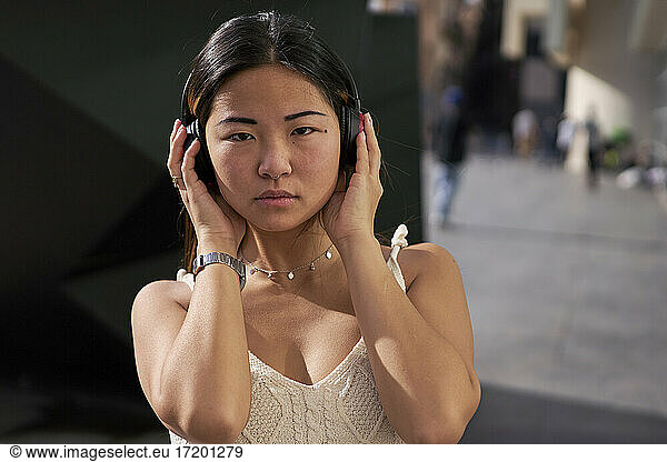 Young woman listening music through headphones outdoors