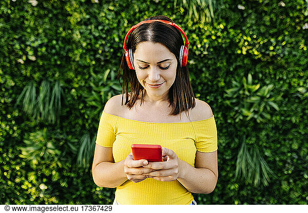 Young woman listening music through headphones while using smart phone