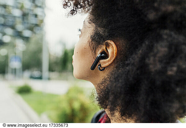 Young woman listening music through wireless in-ear headphones