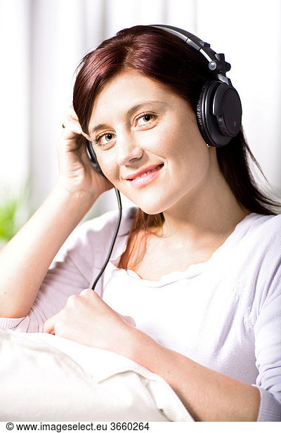 Young woman listening to music on headphones in the living room