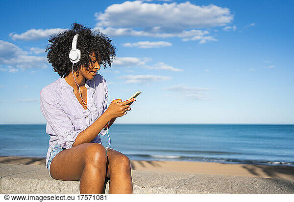 Young woman listening to music on the beach wearing headphones