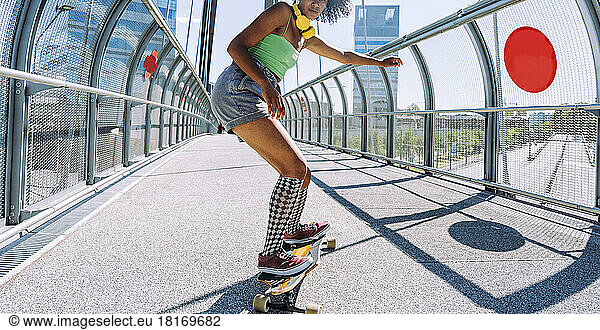 Young woman longboard dancing on bridge