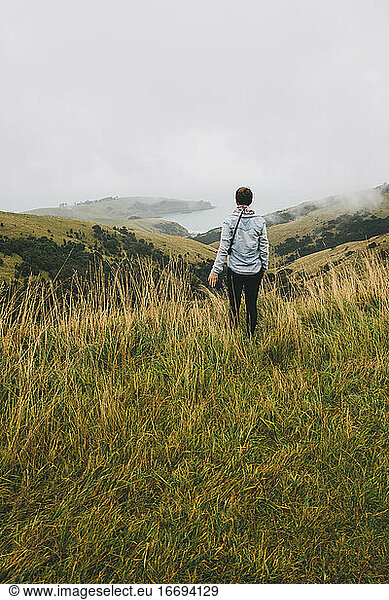 Young woman looking at Little Akaloa  Banks Peninsula  New Zealand