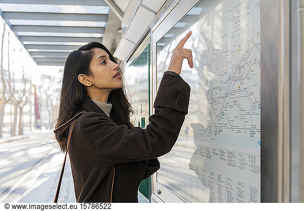 Young woman looking at map at the tram stop