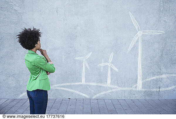 Young woman looking at painted wind turbines on wall