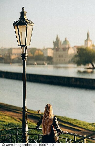 Young woman looking at panoramic city view in autumn Prague