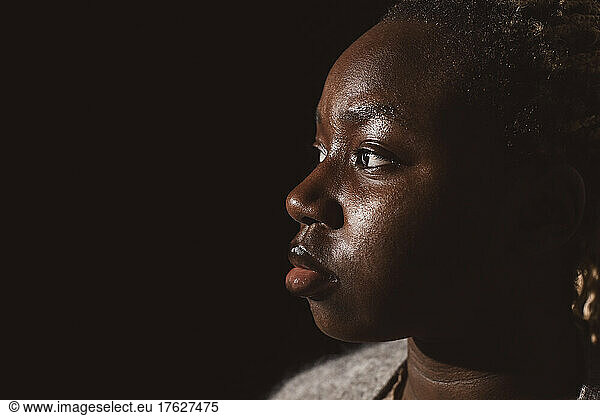 Young woman looking away by black background